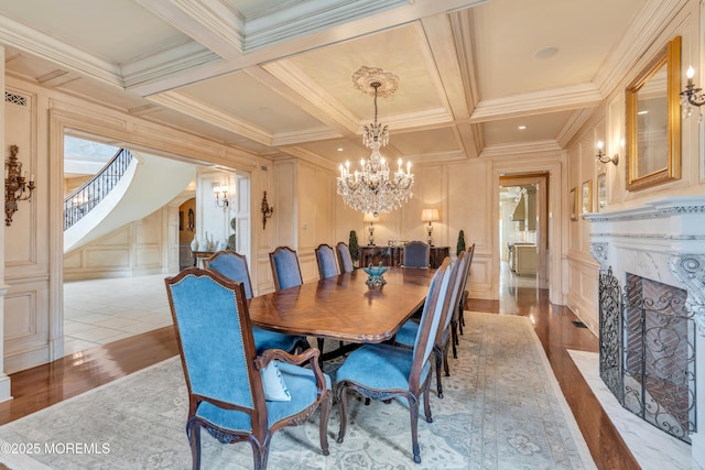 dining room featuring a decorative wall, a chandelier, beam ceiling, wood finished floors, and coffered ceiling