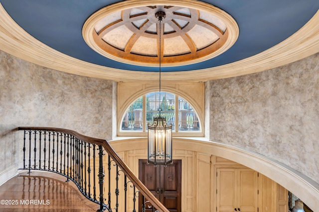 staircase with a notable chandelier, ornamental molding, and a towering ceiling