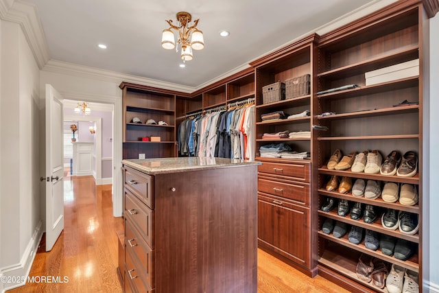 walk in closet with light wood finished floors and a notable chandelier