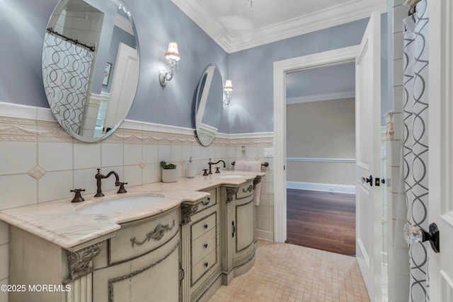 full bathroom with a sink, tile walls, double vanity, and crown molding