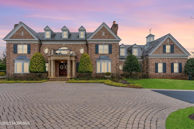 colonial house featuring brick siding and a chimney