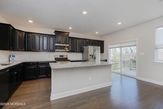 kitchen with dark wood finished floors, a center island, appliances with stainless steel finishes, and backsplash