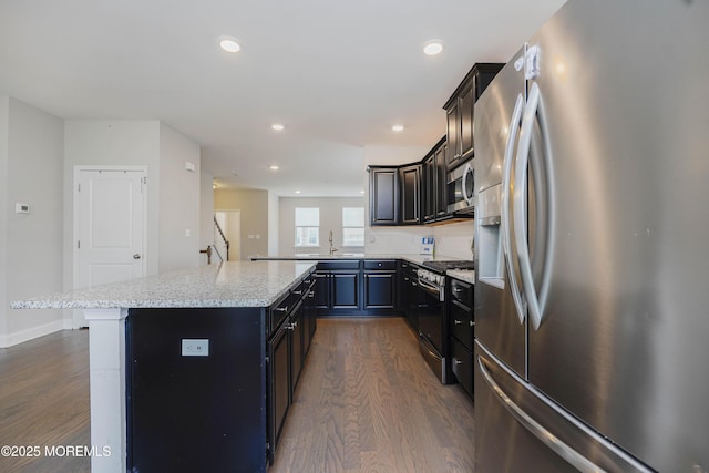 kitchen featuring dark wood finished floors, recessed lighting, a center island, a sink, and stainless steel appliances