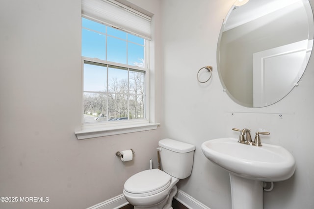 half bath with baseboards and toilet