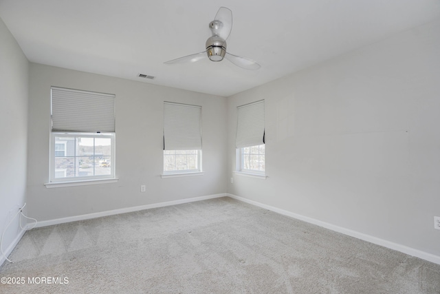 carpeted spare room featuring visible vents, baseboards, and a ceiling fan