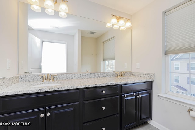 bathroom featuring double vanity, visible vents, baseboards, and a sink