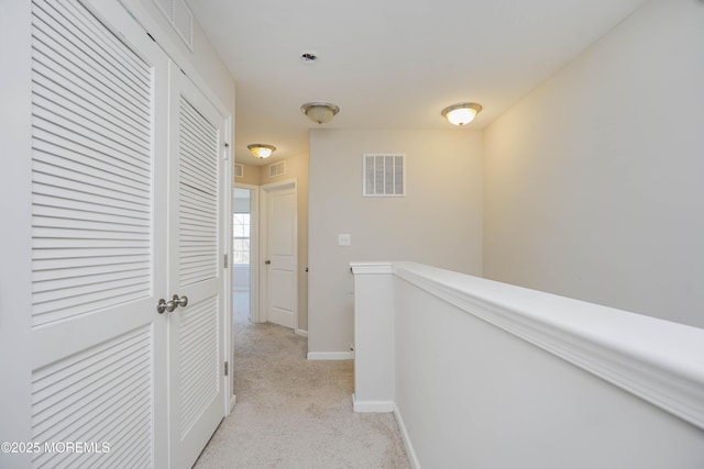 hallway featuring an upstairs landing, visible vents, light colored carpet, and baseboards