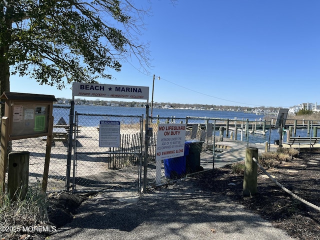 view of dock with fence, a water view, and a gate