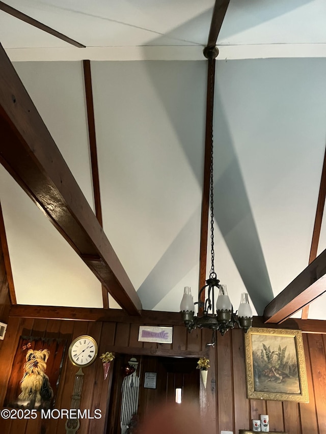 interior details with an inviting chandelier, wood walls, and beamed ceiling