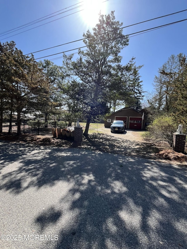 exterior space with an outbuilding, a detached garage, fence, and driveway