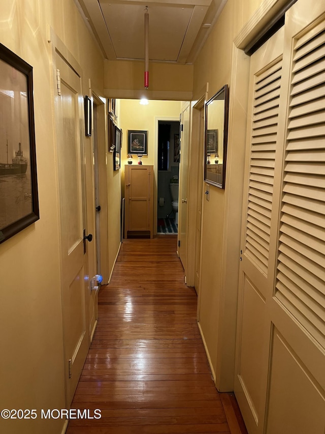 corridor with wood-type flooring and attic access