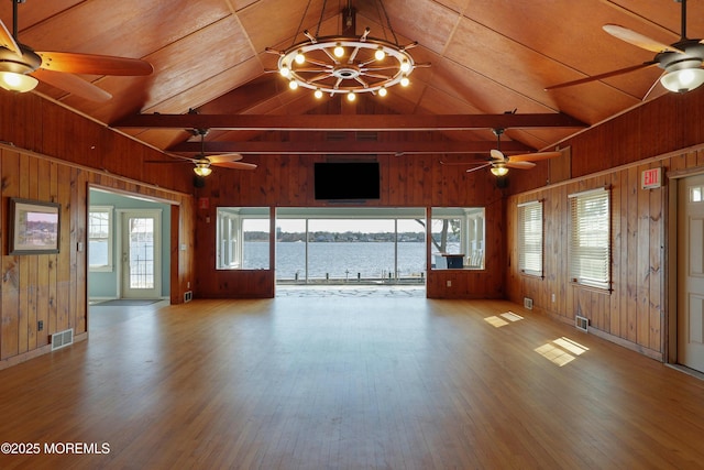 unfurnished living room featuring ceiling fan with notable chandelier, wood walls, and visible vents