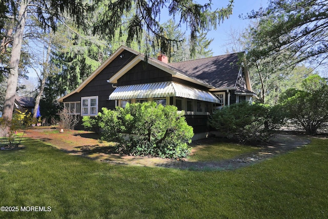 view of property exterior featuring roof with shingles, a yard, and a chimney