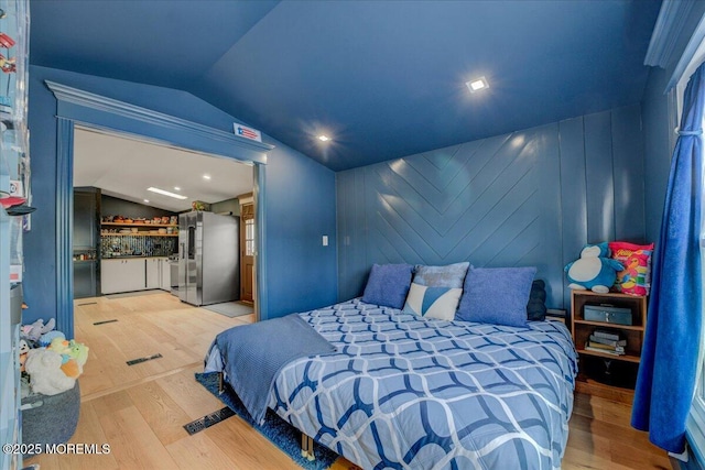 bedroom featuring vaulted ceiling, wood finished floors, bar, and freestanding refrigerator