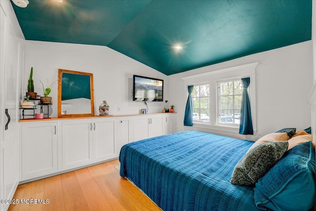 bedroom with light wood-style floors and lofted ceiling