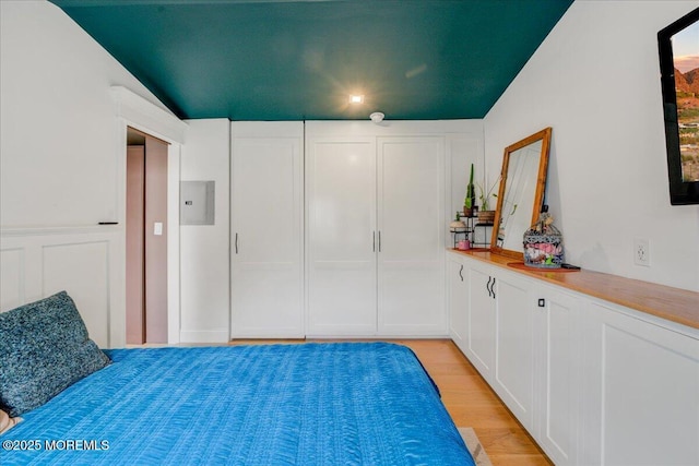 bedroom with electric panel and light wood-style floors
