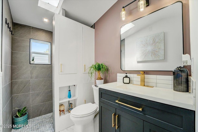bathroom with toilet, a skylight, a walk in shower, and vanity