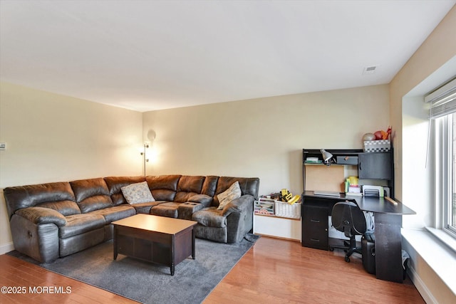 living room with visible vents, baseboards, and wood finished floors
