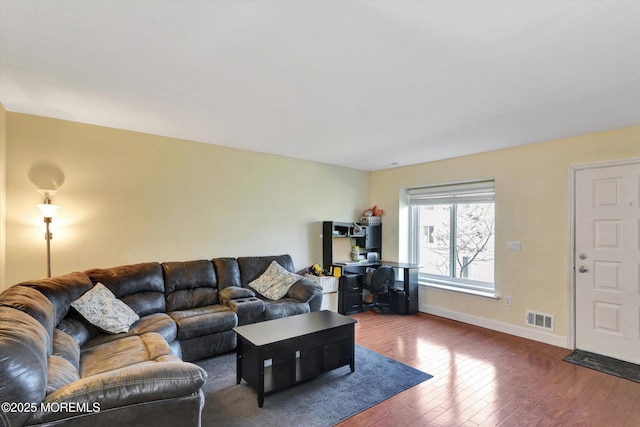 living area featuring dark wood-type flooring, visible vents, and baseboards