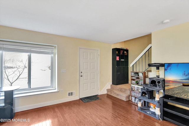 foyer with visible vents, baseboards, wood finished floors, and stairs