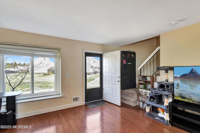 foyer entrance featuring wood finished floors, baseboards, visible vents, and stairs