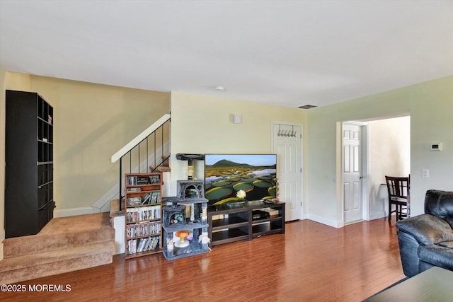 living area with visible vents, baseboards, stairway, and wood finished floors