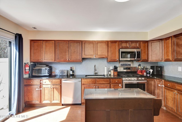 kitchen with a sink, backsplash, brown cabinetry, and stainless steel appliances