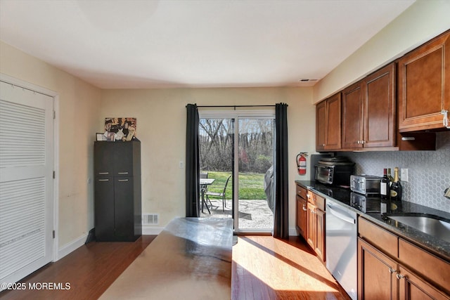 kitchen featuring dark wood-style floors, visible vents, decorative backsplash, dishwasher, and a sink