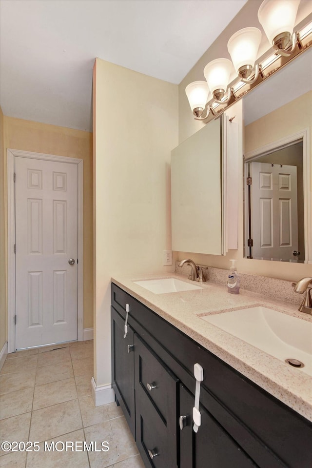 full bathroom featuring tile patterned floors, double vanity, baseboards, and a sink