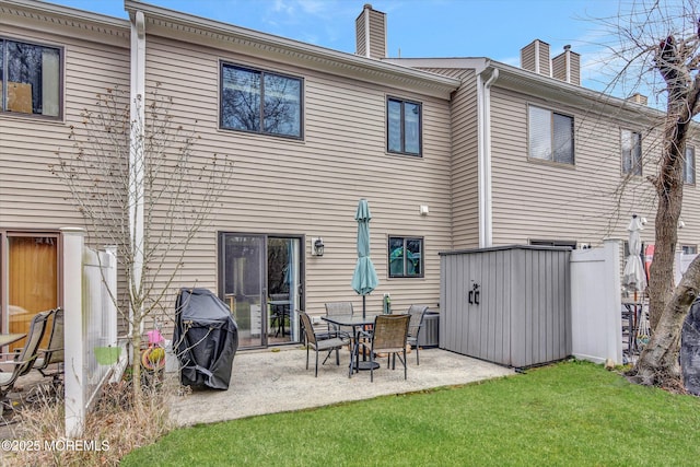 rear view of house featuring a patio area, a chimney, and a lawn