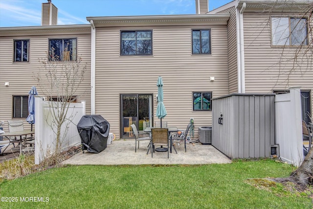 back of property with a patio area, central air condition unit, a chimney, and a yard