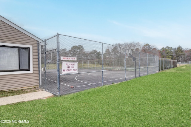 view of sport court with community basketball court, fence, and a lawn