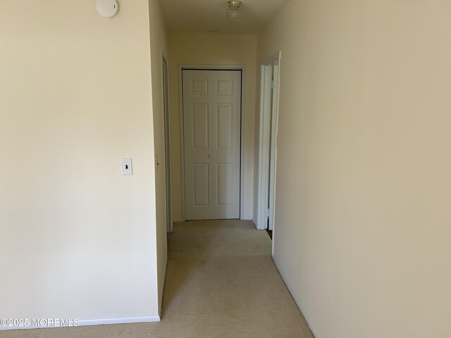 corridor featuring baseboards and light carpet