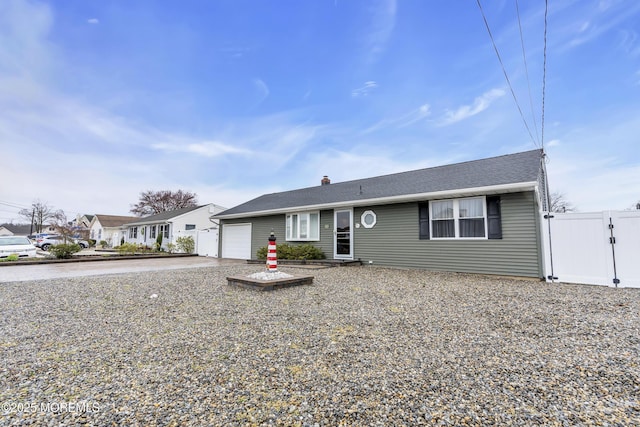 single story home with an attached garage, a chimney, driveway, and fence