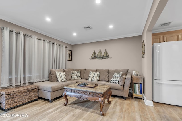 living room featuring light wood finished floors, visible vents, and ornamental molding