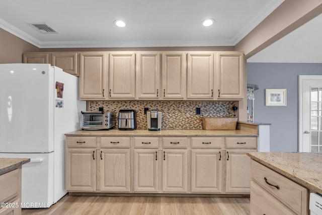 kitchen featuring ornamental molding, backsplash, freestanding refrigerator, visible vents, and light brown cabinetry