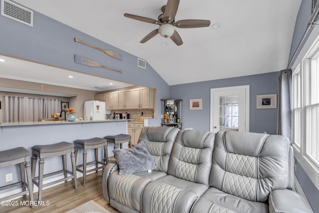 living area with visible vents, vaulted ceiling, light wood-style flooring, and ceiling fan