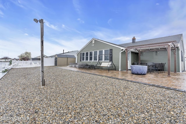 back of property with a shed, a chimney, fence, a patio, and an outbuilding