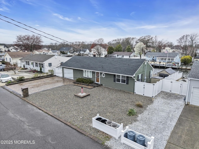 ranch-style home featuring a residential view, fence, a gate, a shingled roof, and concrete driveway