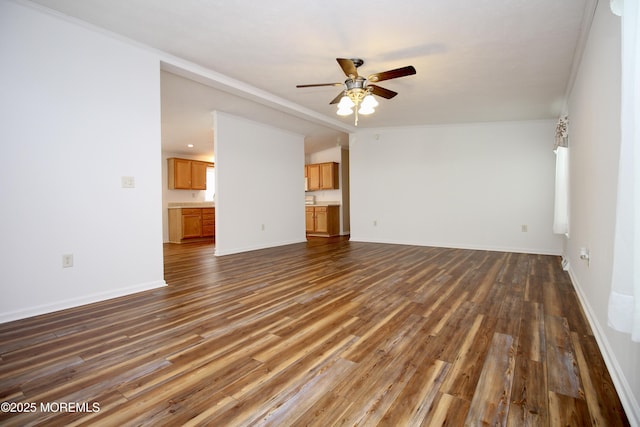 unfurnished living room featuring dark wood-style flooring, ceiling fan, baseboards, and crown molding