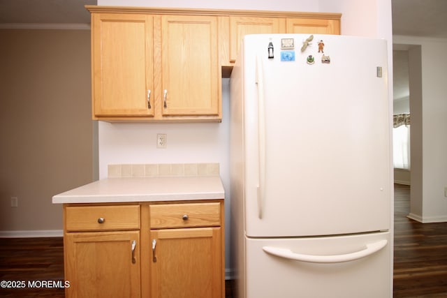 kitchen featuring freestanding refrigerator, dark wood-type flooring, ornamental molding, light countertops, and baseboards