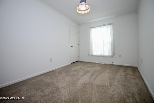 spare room with crown molding, carpet floors, baseboards, and visible vents