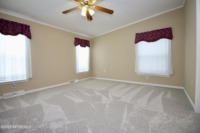 spare room featuring a ceiling fan, ornamental molding, visible vents, and a wealth of natural light