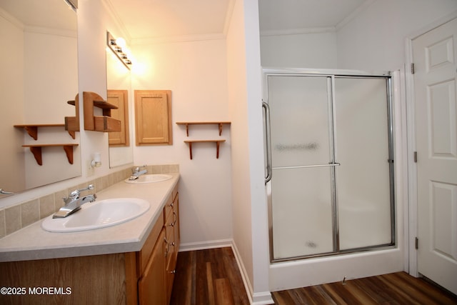 full bath featuring a shower stall, crown molding, wood finished floors, and a sink