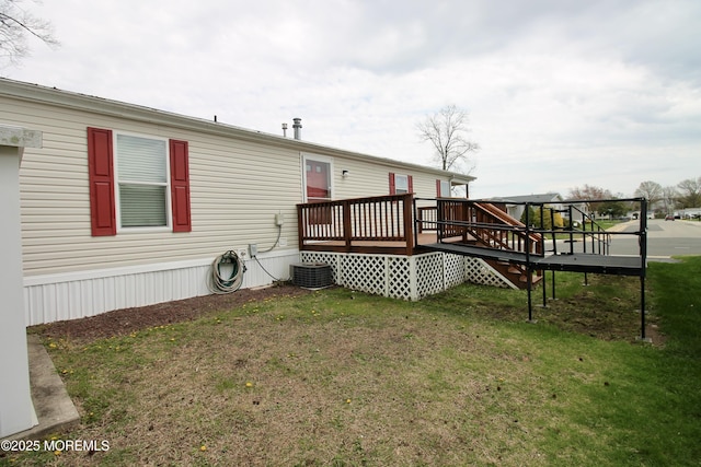 rear view of property with central AC, a deck, and a lawn