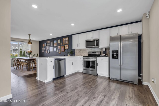 kitchen featuring a peninsula, appliances with stainless steel finishes, dark wood-type flooring, and white cabinets
