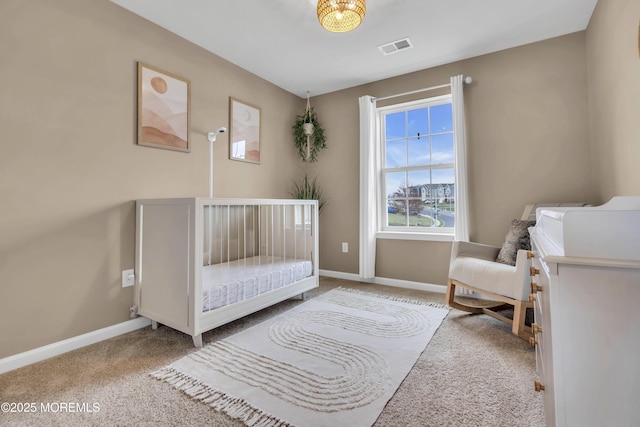 carpeted bedroom featuring baseboards, a crib, and visible vents