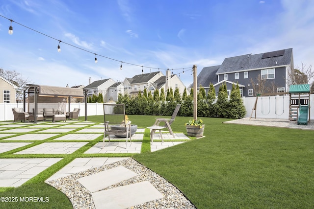 view of yard featuring a residential view, an outdoor living space with a fire pit, a fenced backyard, a playground, and a patio
