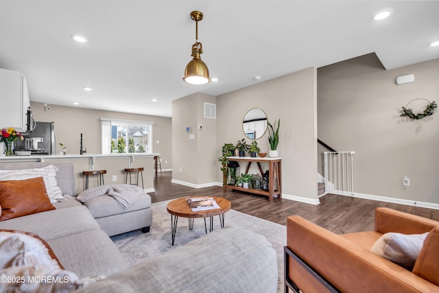 living room featuring dark wood-style floors, baseboards, stairs, and visible vents
