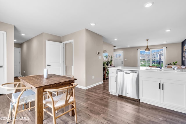 kitchen with dishwasher, white cabinetry, wood finished floors, and a sink